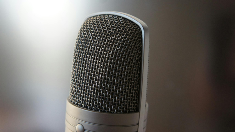 Detailed view of a professional condenser microphone with a blurred backdrop, ideal for audio equipment themes.